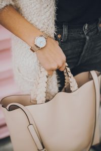 Woman's wristwatch and beige handbag.