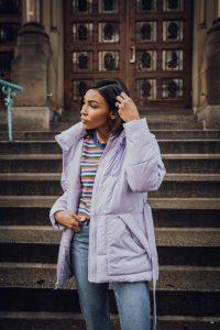 Woman in lavender puffer jacket on steps.