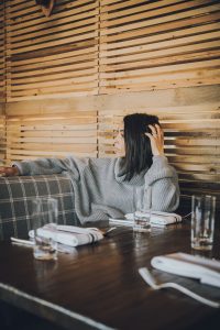 Woman in grey sweater at restaurant.