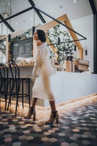 Woman in white dress and leopard boots.