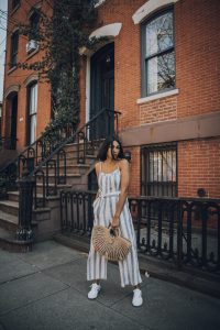 Woman in striped jumpsuit, city street.