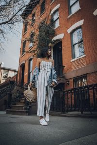 Woman in striped jumpsuit walking city street.