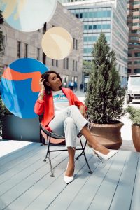 Woman in red blazer sitting outdoors.