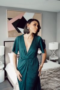 Woman in teal dress, modern earrings.