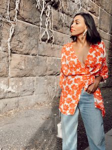 Woman in orange floral shirt and jeans.