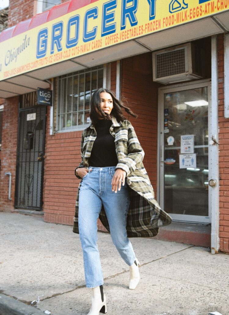 Woman in plaid coat walking past grocery.