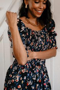 Woman in floral dress, gold jewelry.