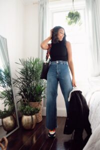 Woman in jeans and black top, plants.